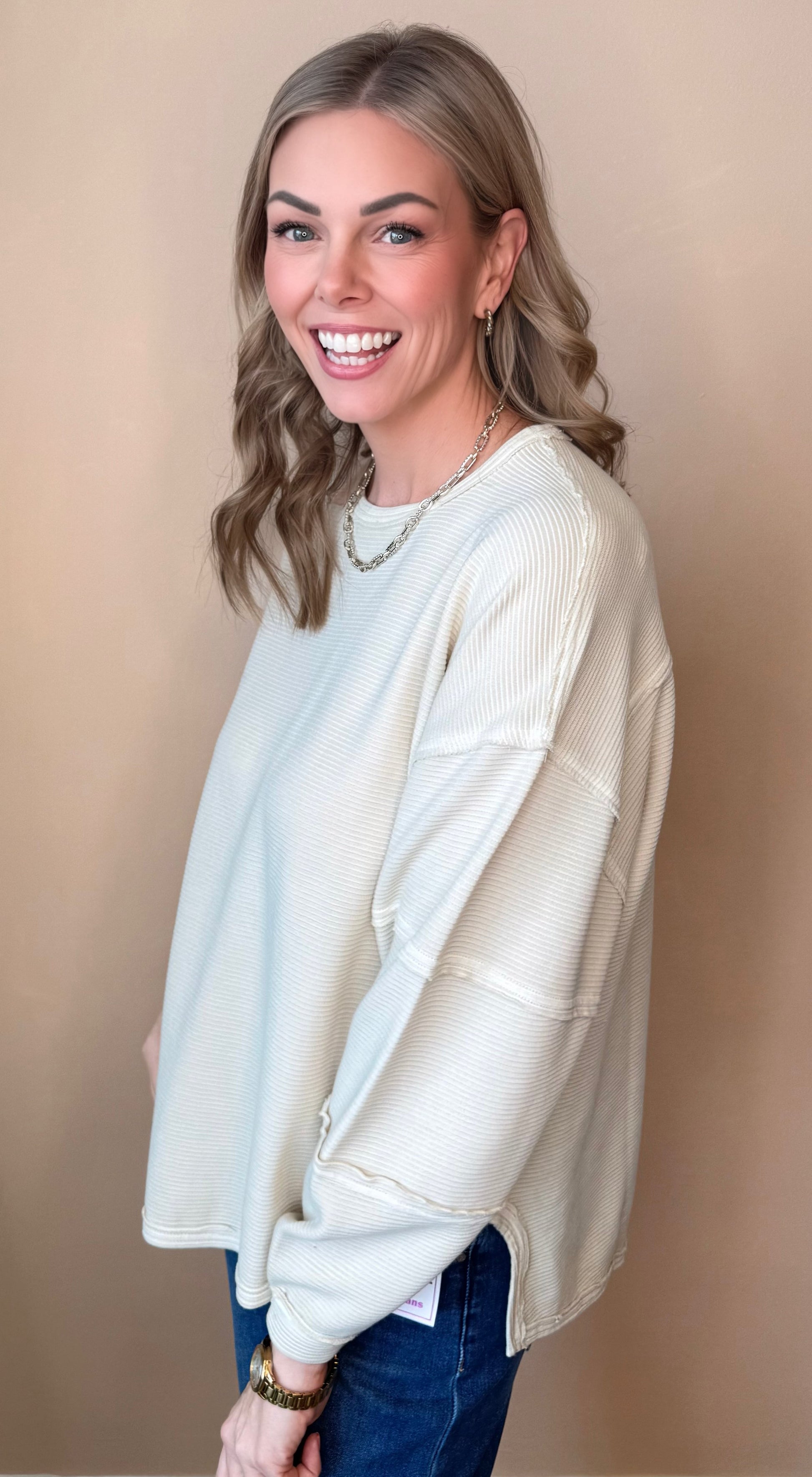 Woman wearing a cream cardigan over a light blue top on a beige background